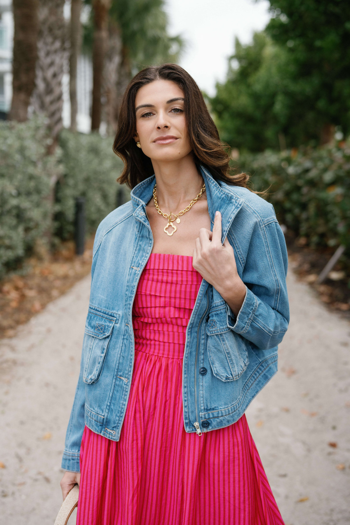 Gold clover pendant necklace on fine chain, worn at the collarbone.