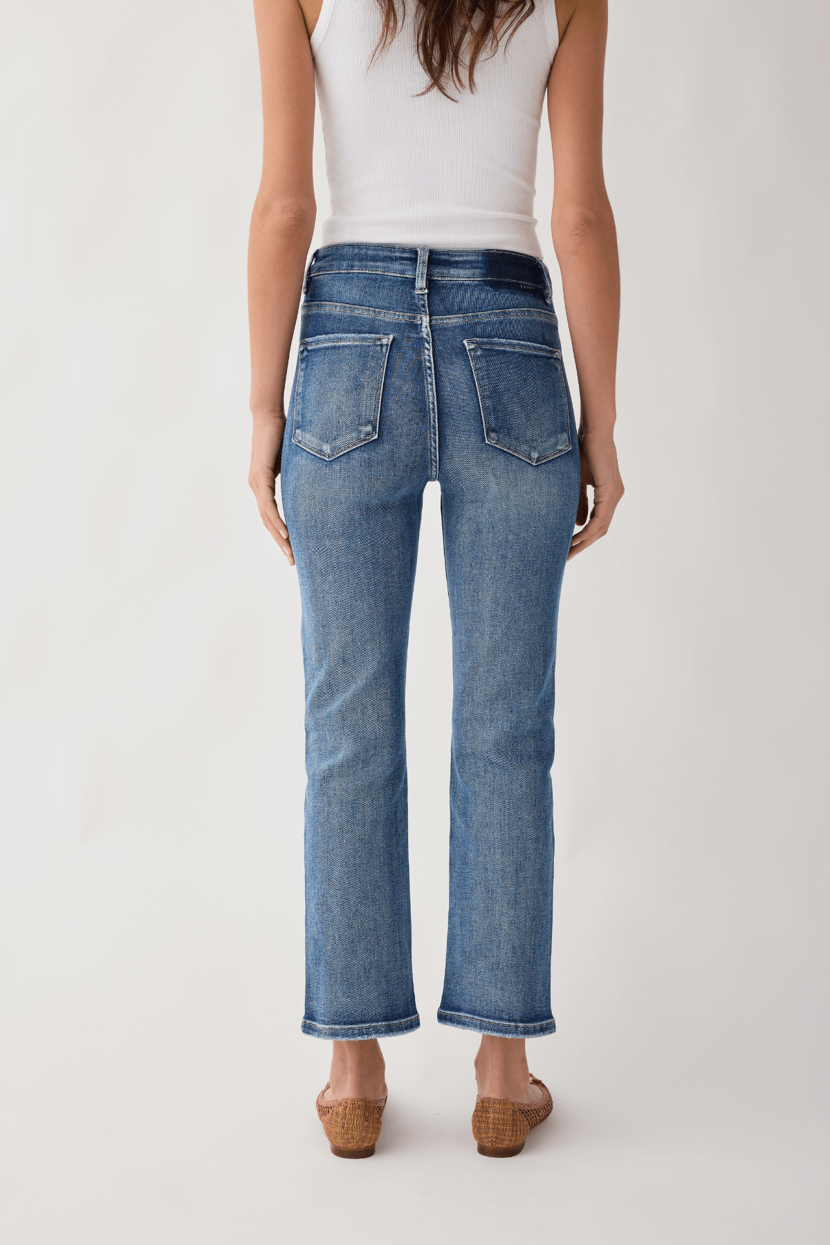 Back view of medium wash straight-leg jeans with two rear pockets, cropped hem.