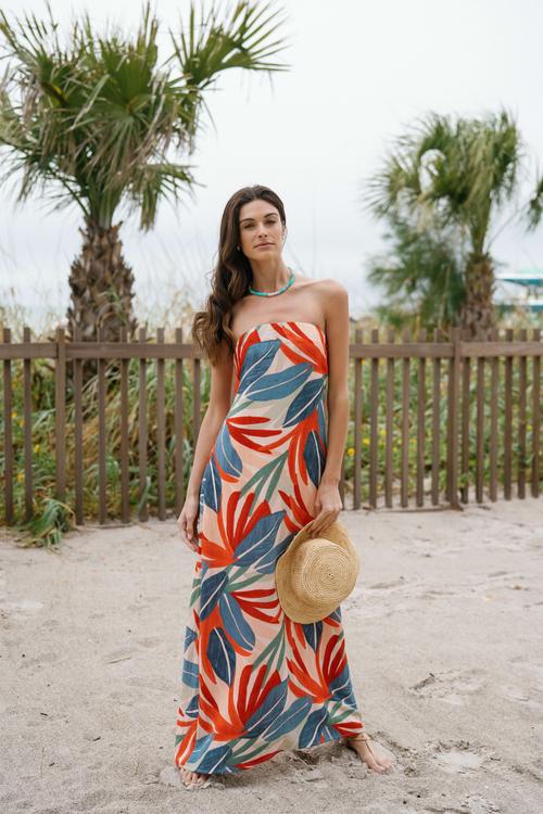 Strapless palm print maxi dress standing pose, orange and blue leaf pattern