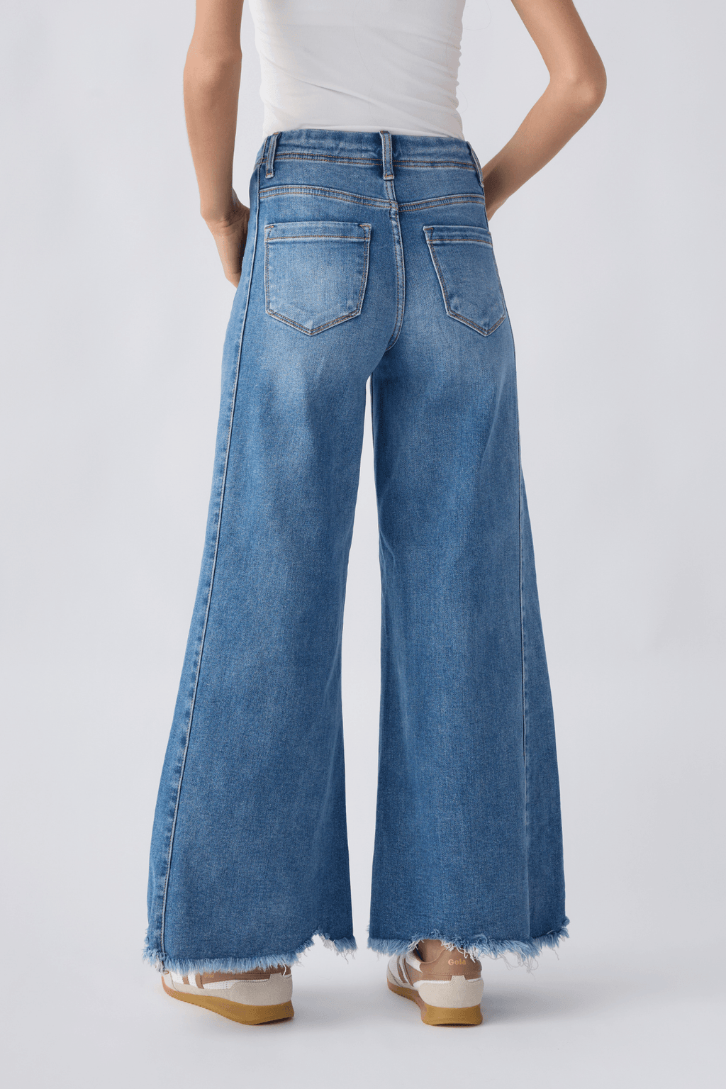 Back view of medium wash high-rise ultra wide leg jeans with two back pockets, frayed hem.