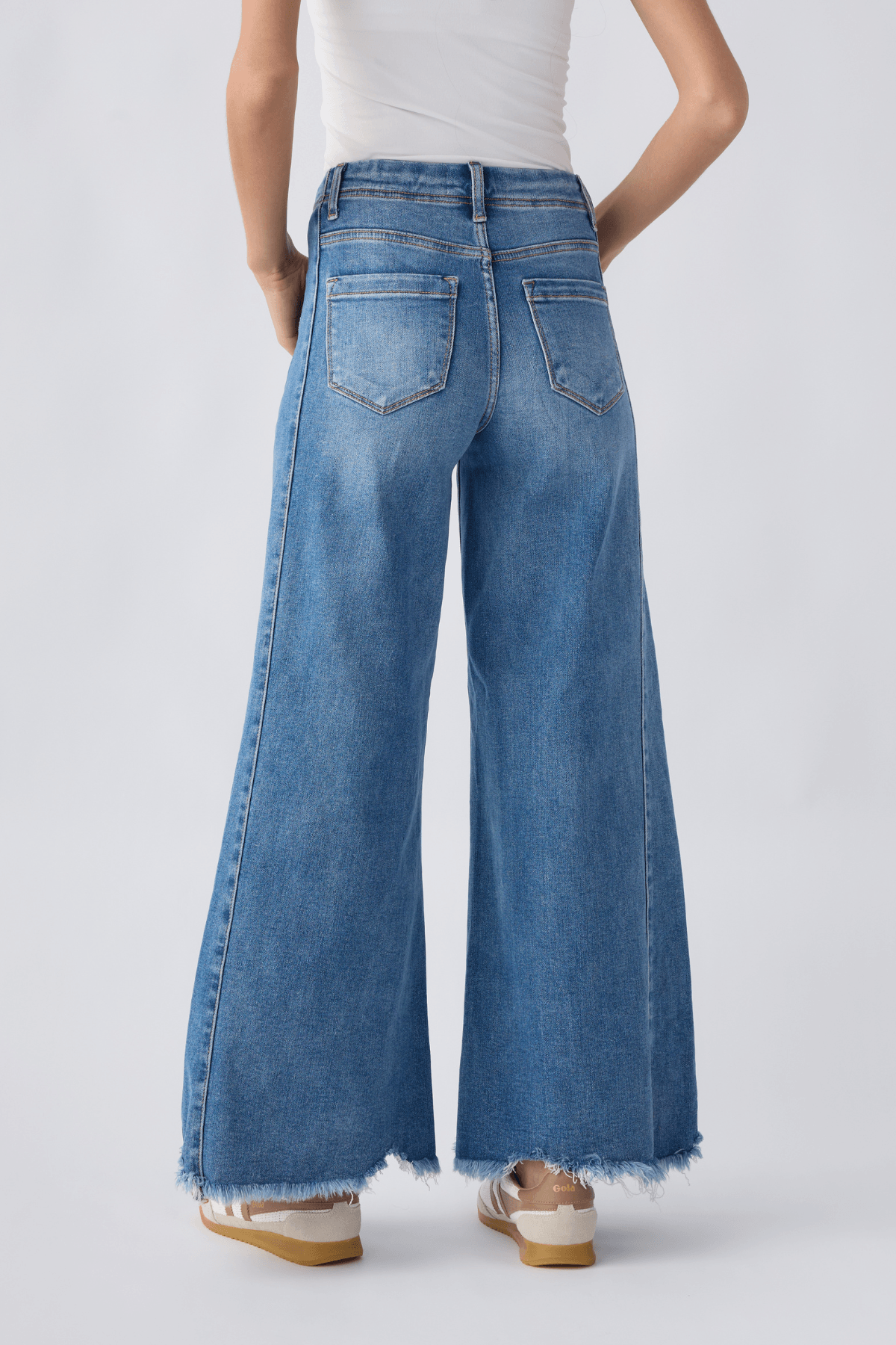 Back view of medium wash high-rise ultra wide leg jeans with two back pockets, frayed hem.