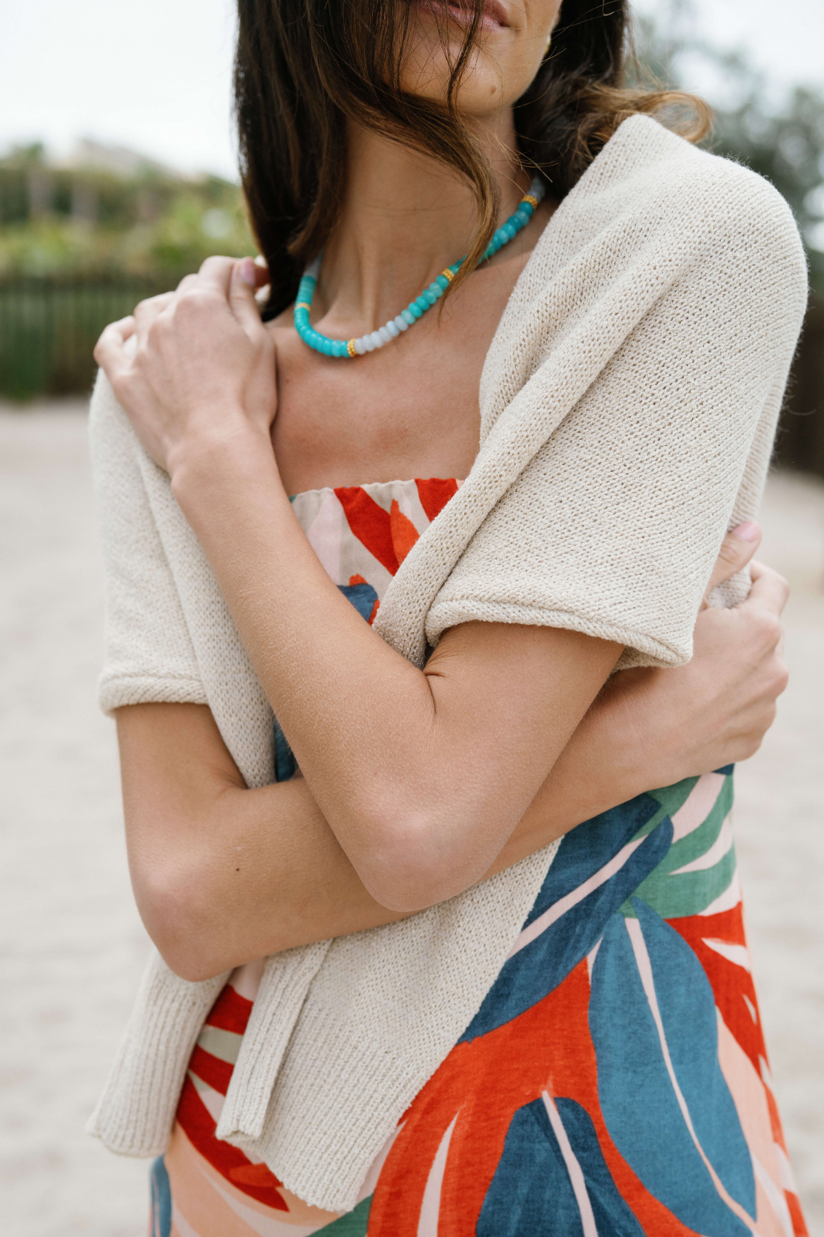 Close-up of strapless palm print maxi dress bodice with turquoise bead necklace