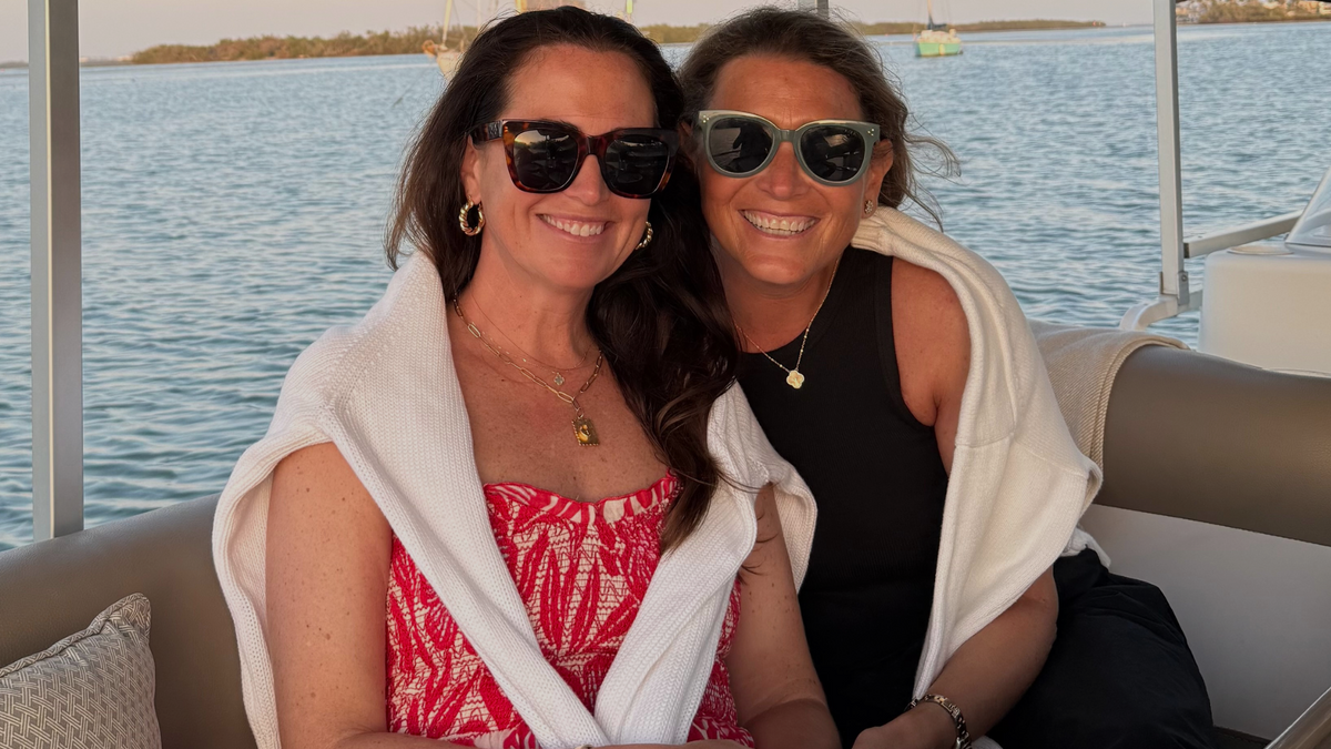 Two women, the founders of Social Threads Sara and Maureen, sitting on a boat with water in the background