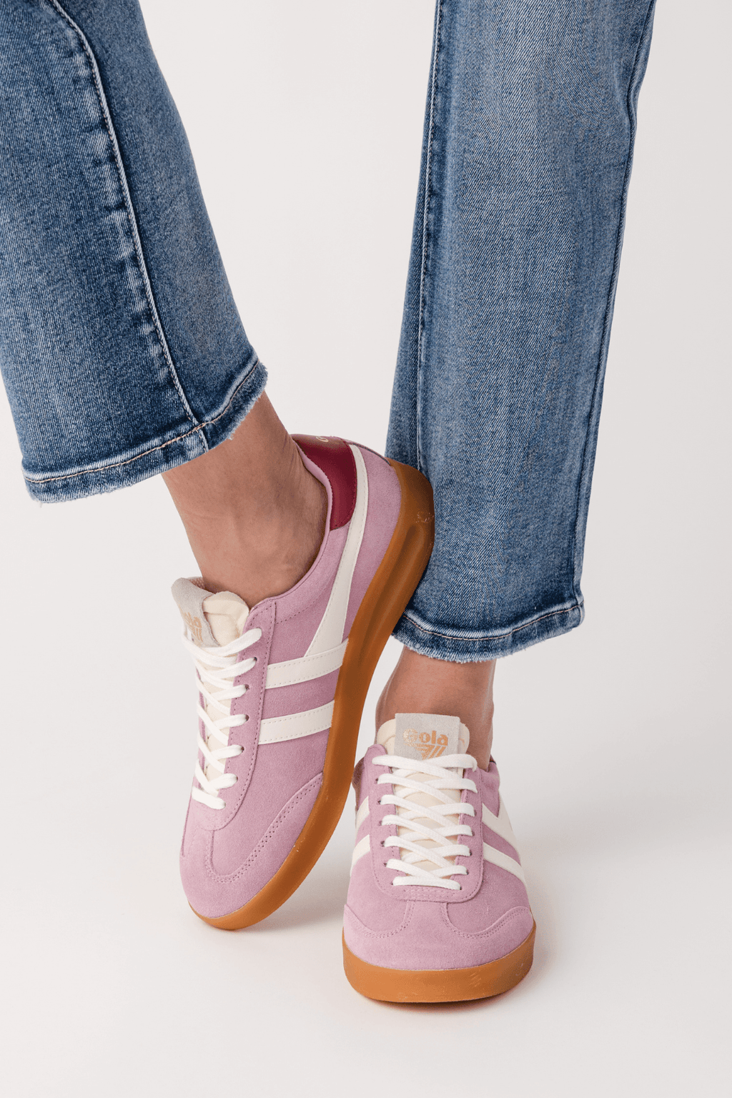Pink suede sneakers with white stripes, lace-up front, and tan/gum sole