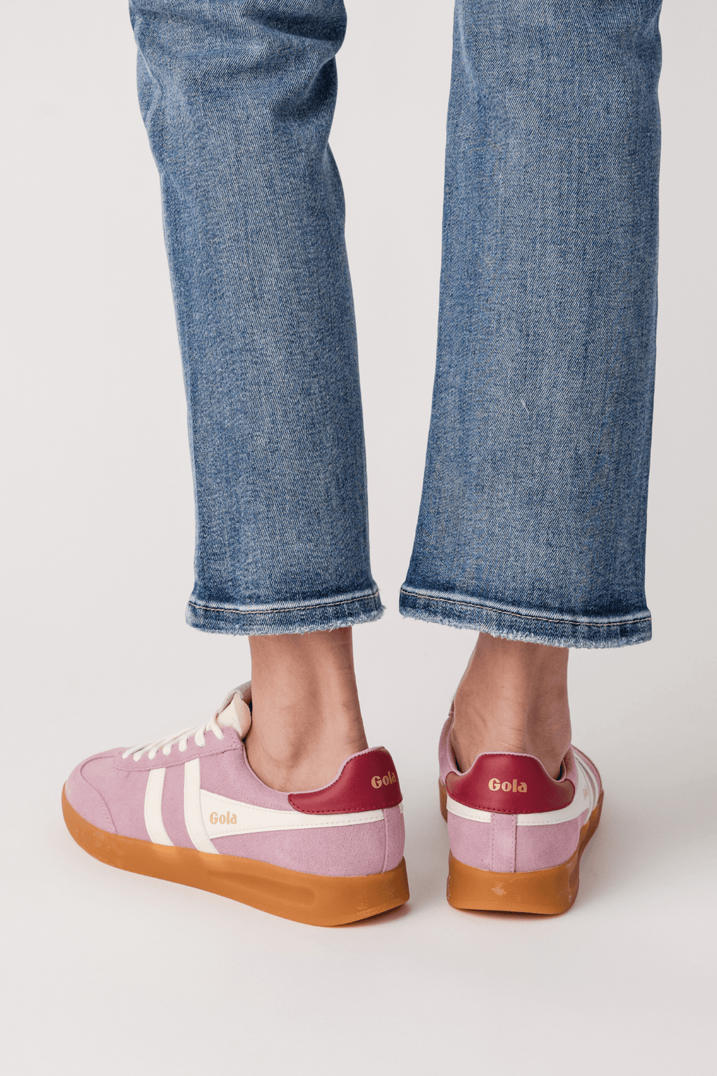 Pink lace-up sneakers showing heel and gum sole with white stripe detailing