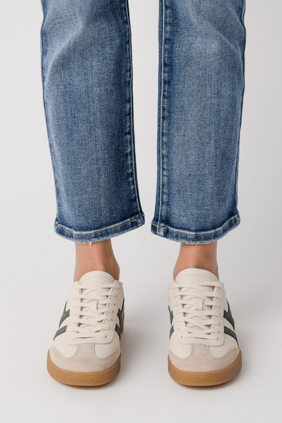 White leather sneakers with gum sole and subtle green accent at heel