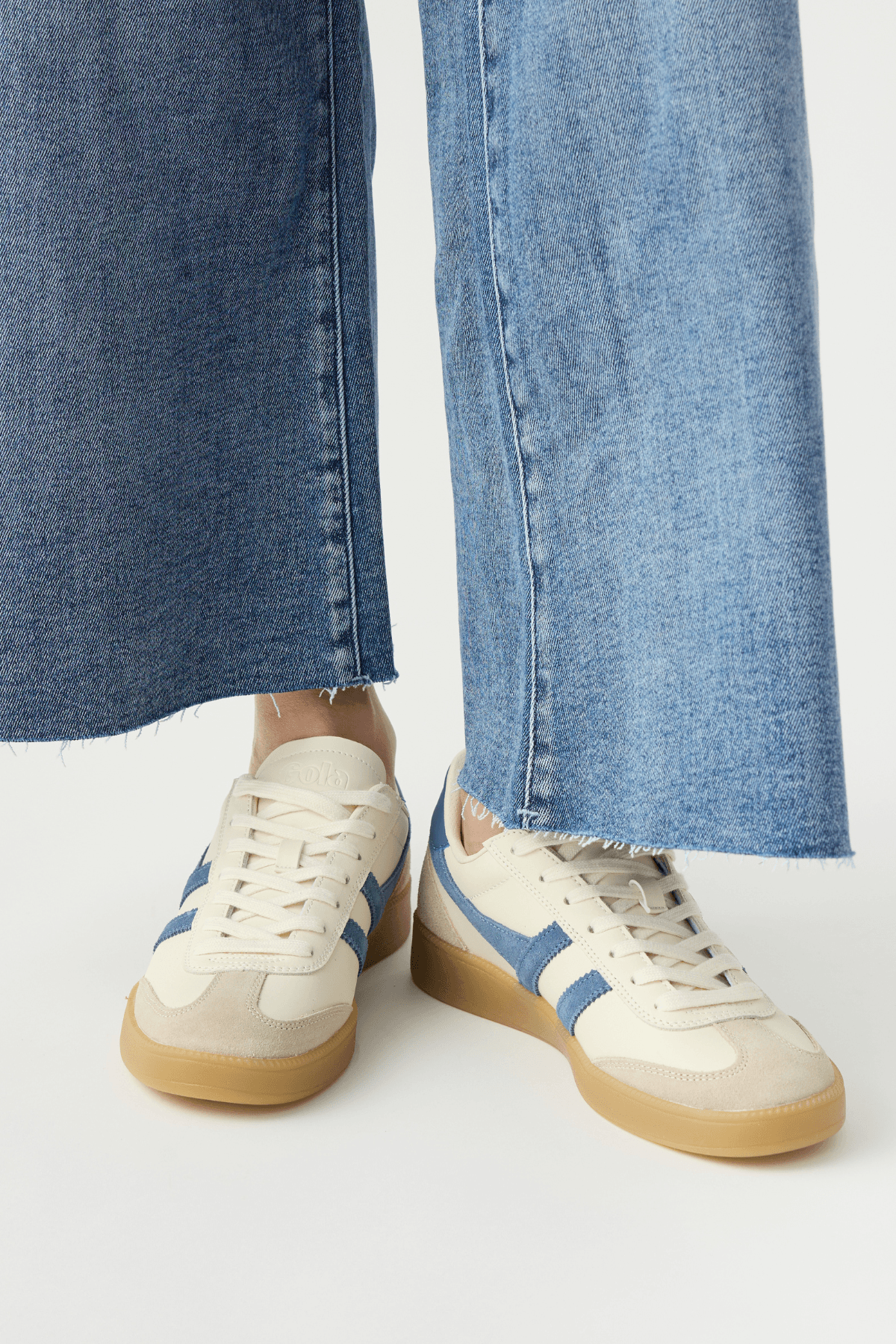 White leather low-top sneakers with blue side stripes and gum rubber sole