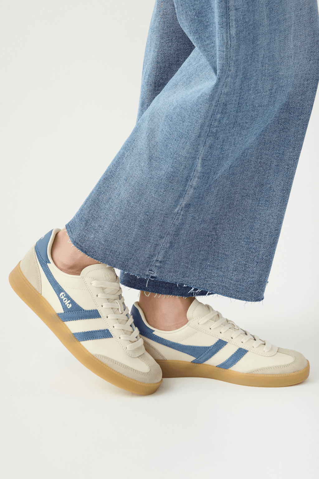 White leather low-top sneakers with blue stripes, lace-up front, and gum rubber sole