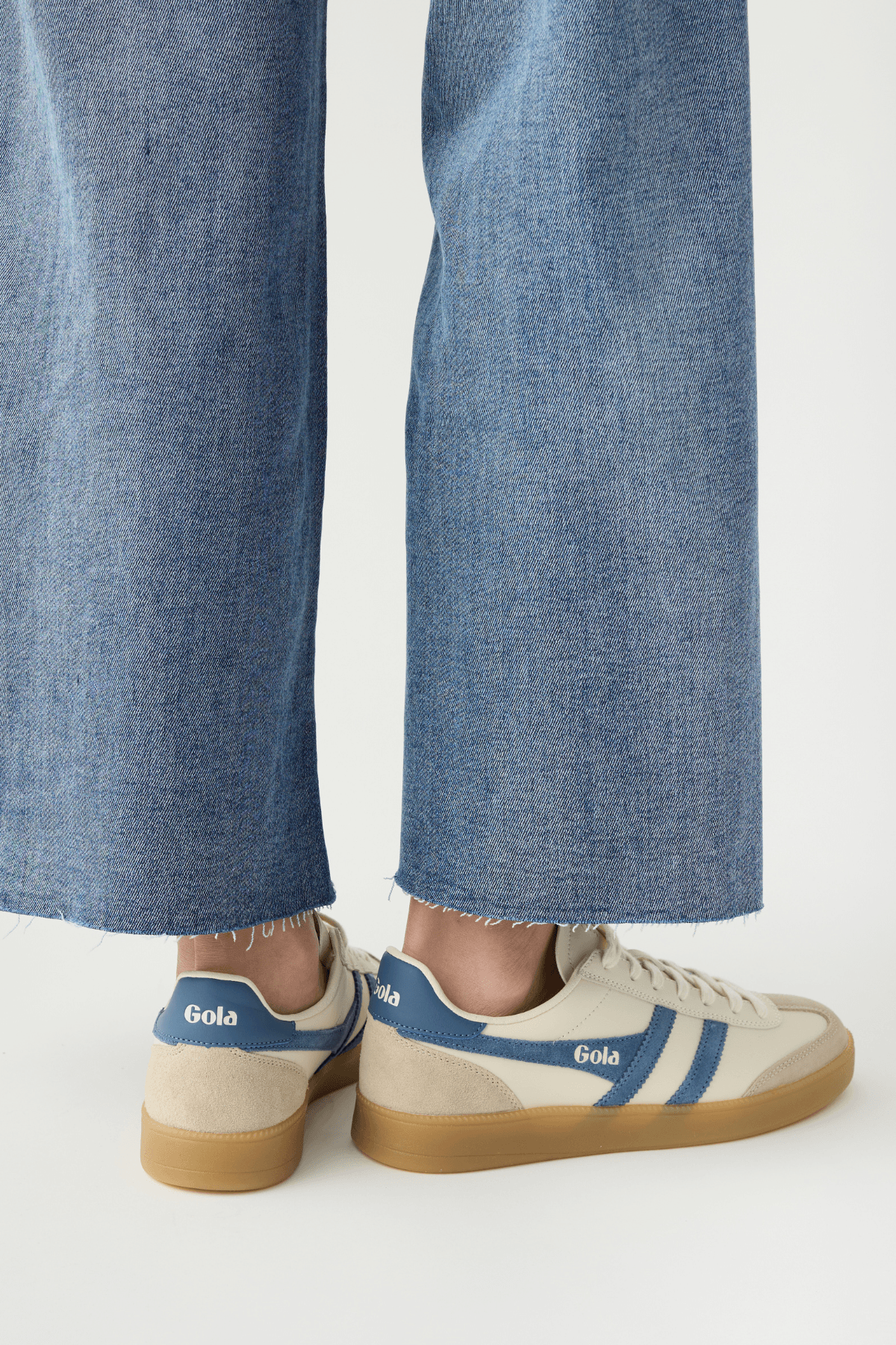 White leather sneakers with blue heel tab, Gola logo, and gum outsole