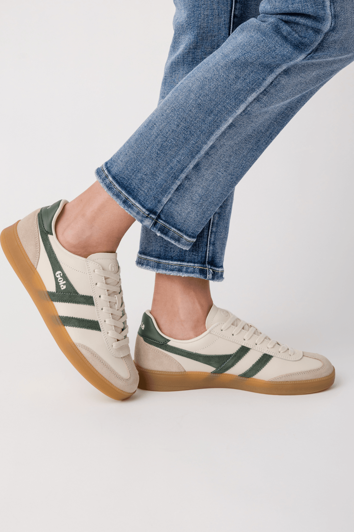 White leather sneakers with green side stripes and tan/gum rubber sole