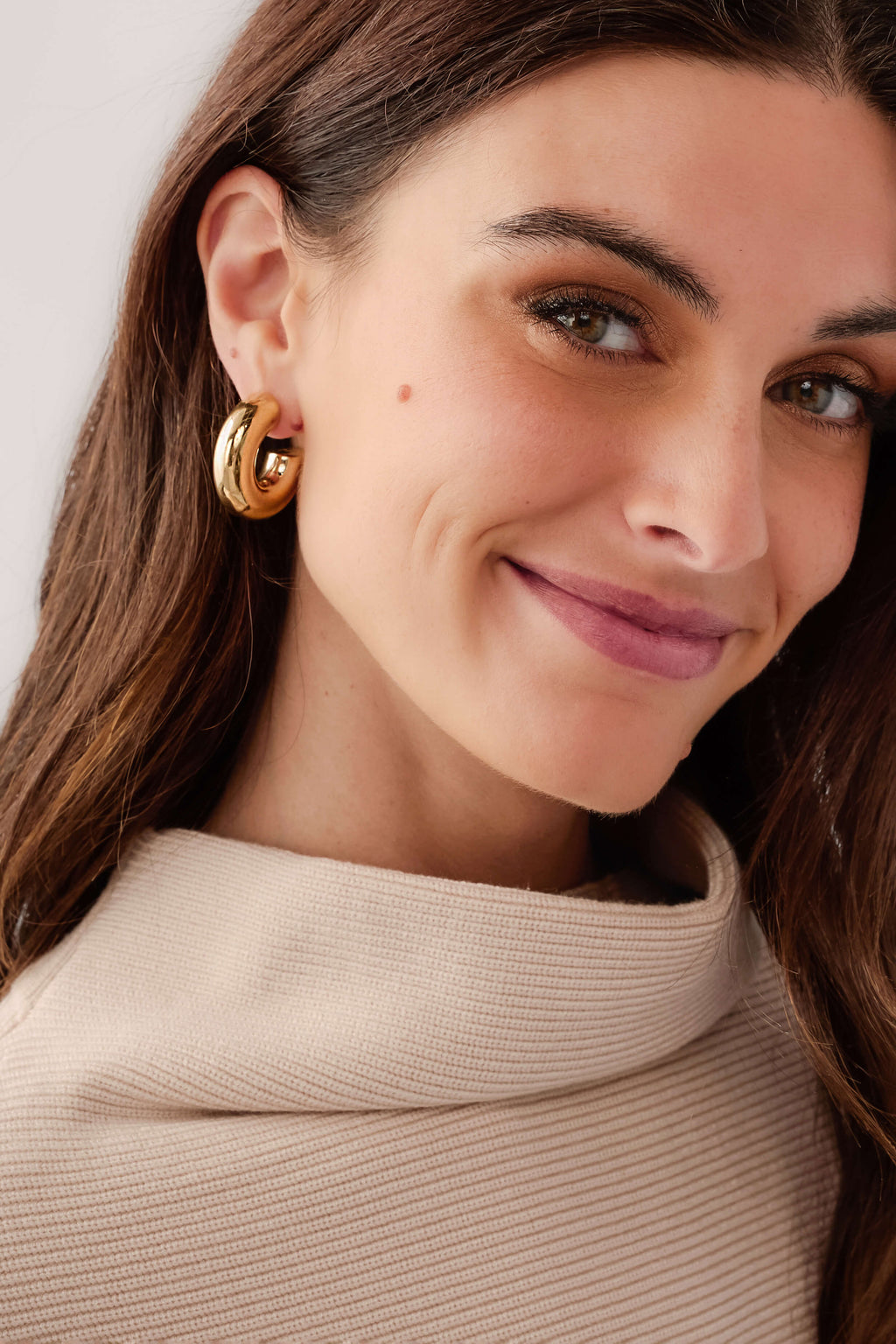Gold hoop earrings worn on model, polished curved hoops with post back