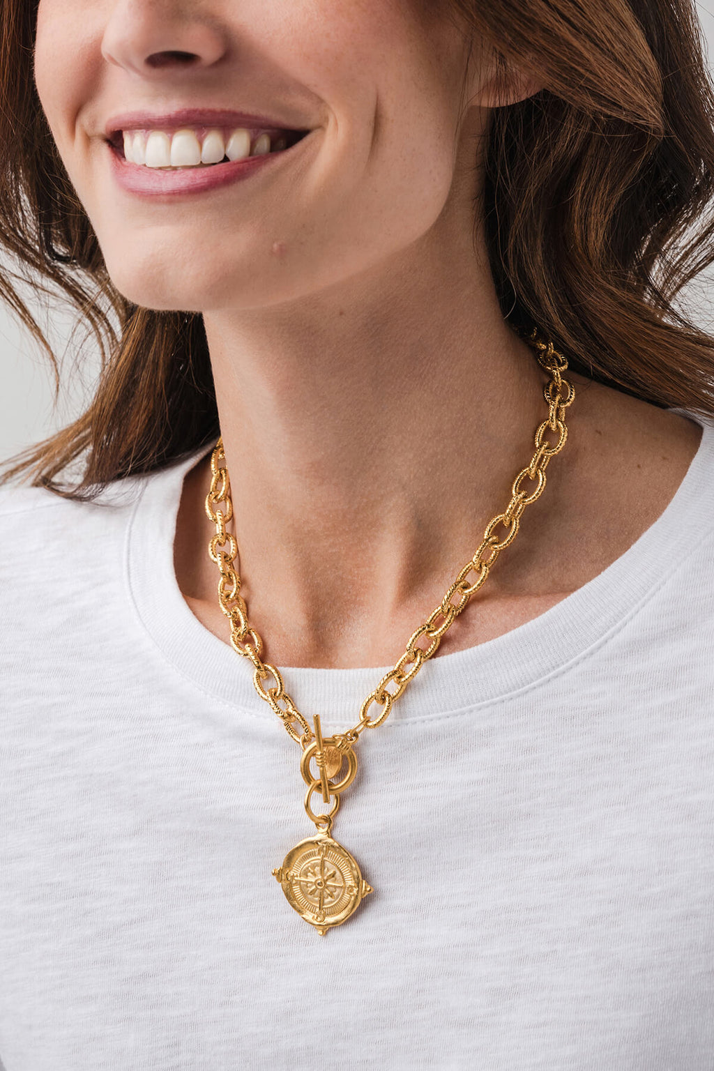 Gold curb-link necklace featuring a large centered compass pendant