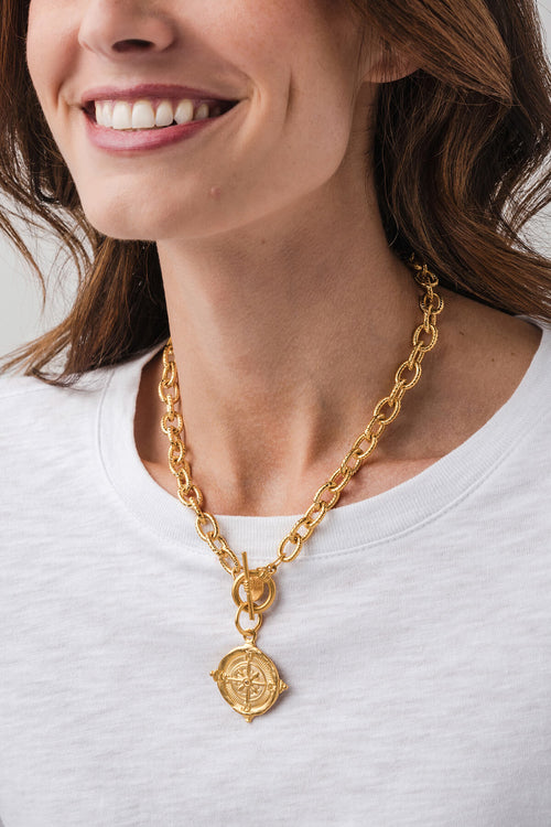 Gold curb-link necklace featuring a large centered compass pendant