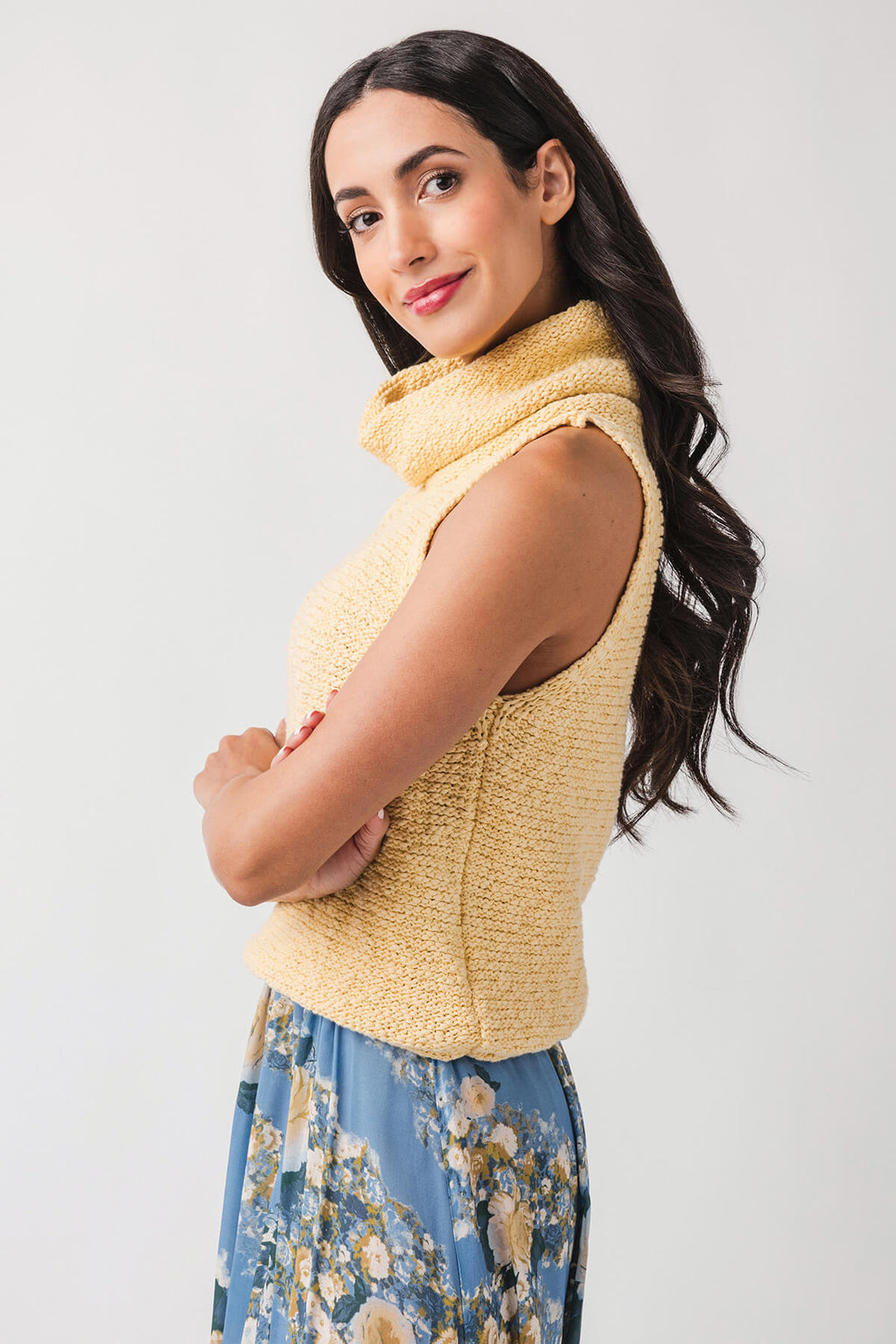 Warm yellow sleeveless knit top from side view with high cowl collar