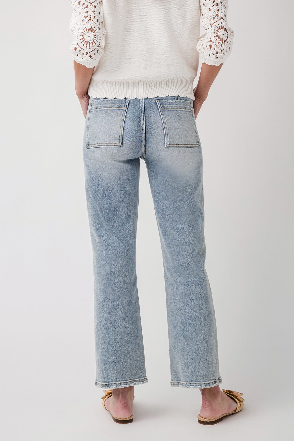 Light blue ankle flare jeans with two back pockets and visible yoke seams, back view