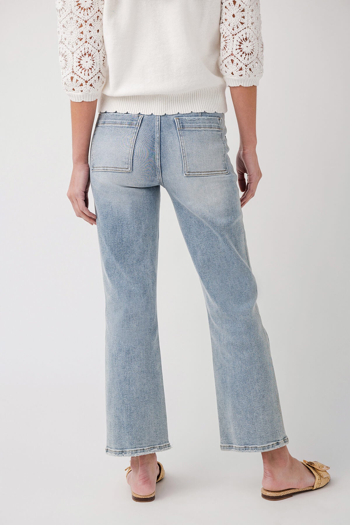 Light blue ankle flare jeans with front crease and belt loops, back view