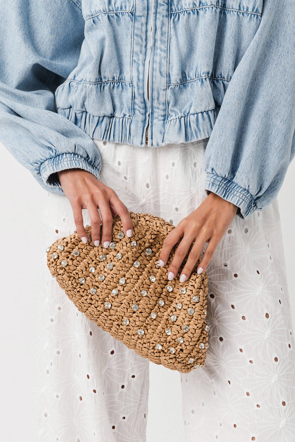 Beaded straw clutch held in hands with chain strap