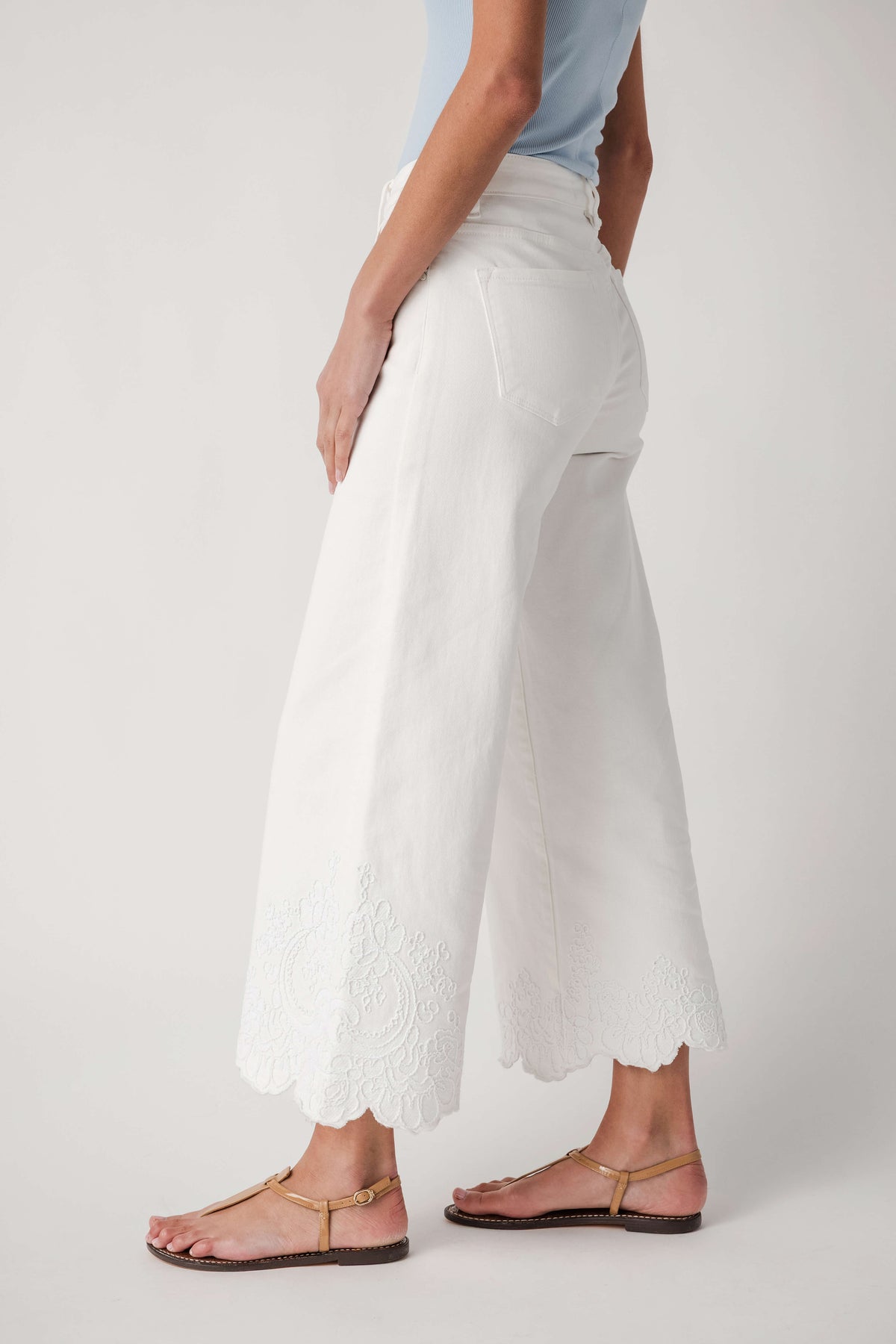 Cream high-rise wide-leg crop pants with lace detailing at the lower hem