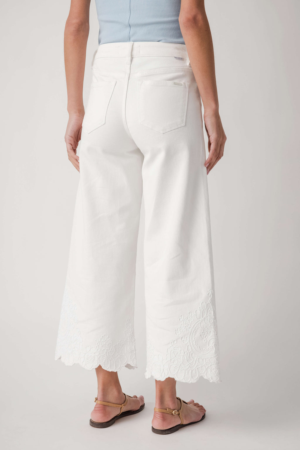 Cream high-rise crop pants with lace-edged wide hems and back patch pockets