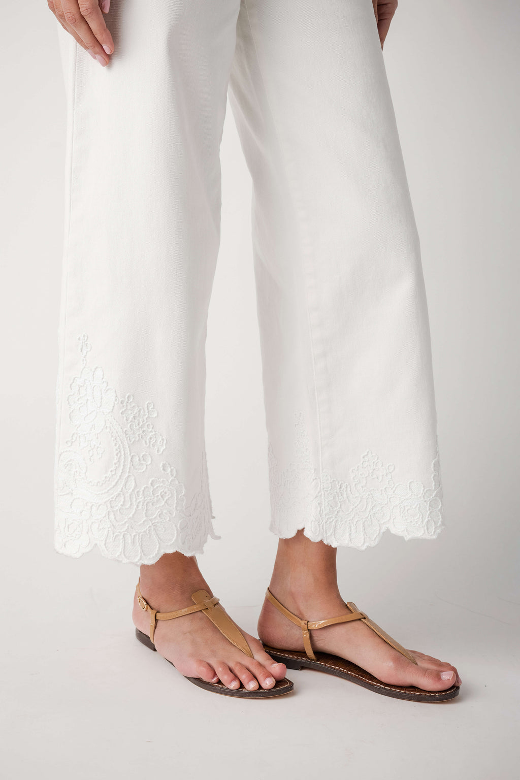 Cream wide-leg crop pants featuring lace panel trim along the leg bottoms