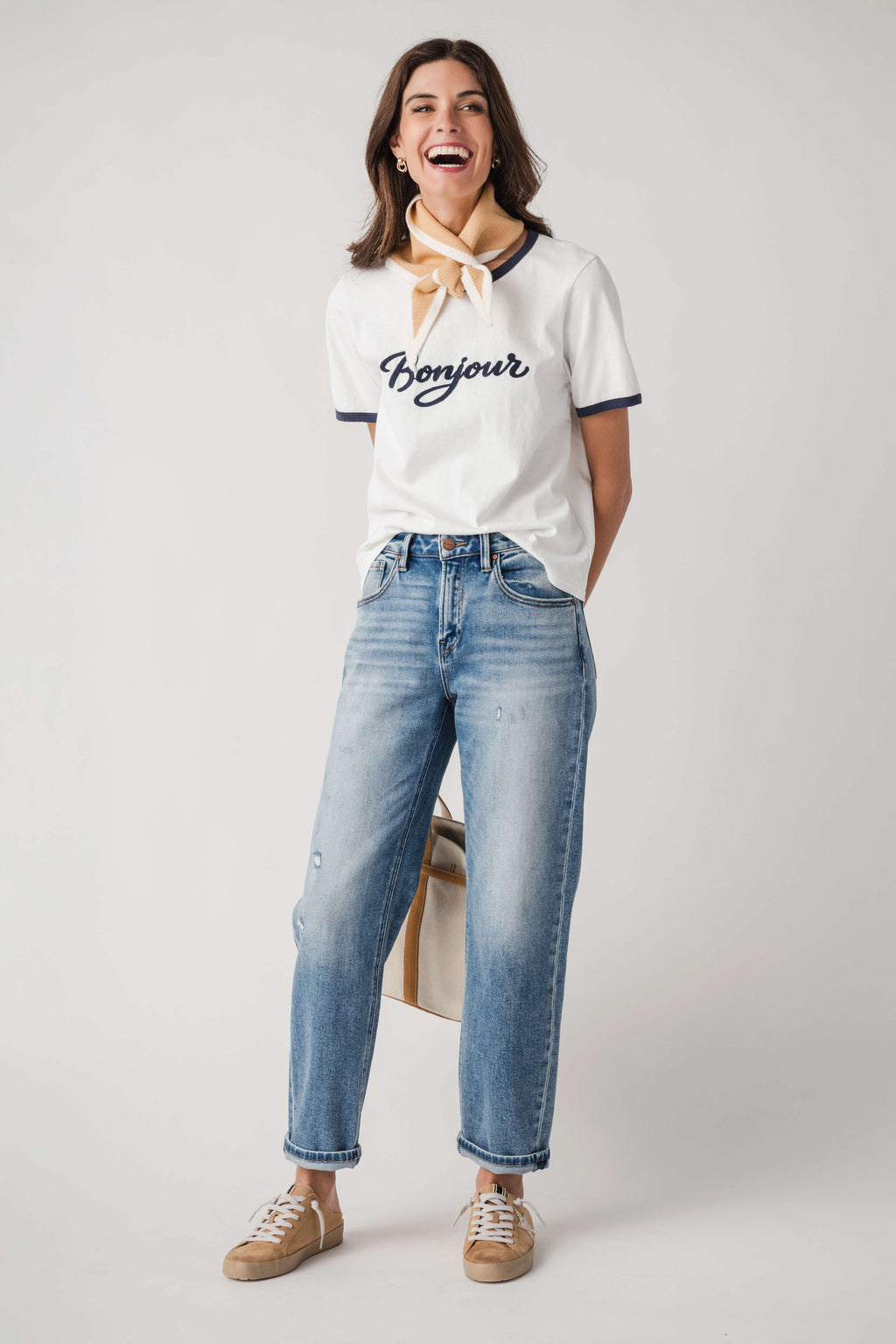 White Bonjour T-shirt with navy trim and bow neck, worn with blue cuffed jeans