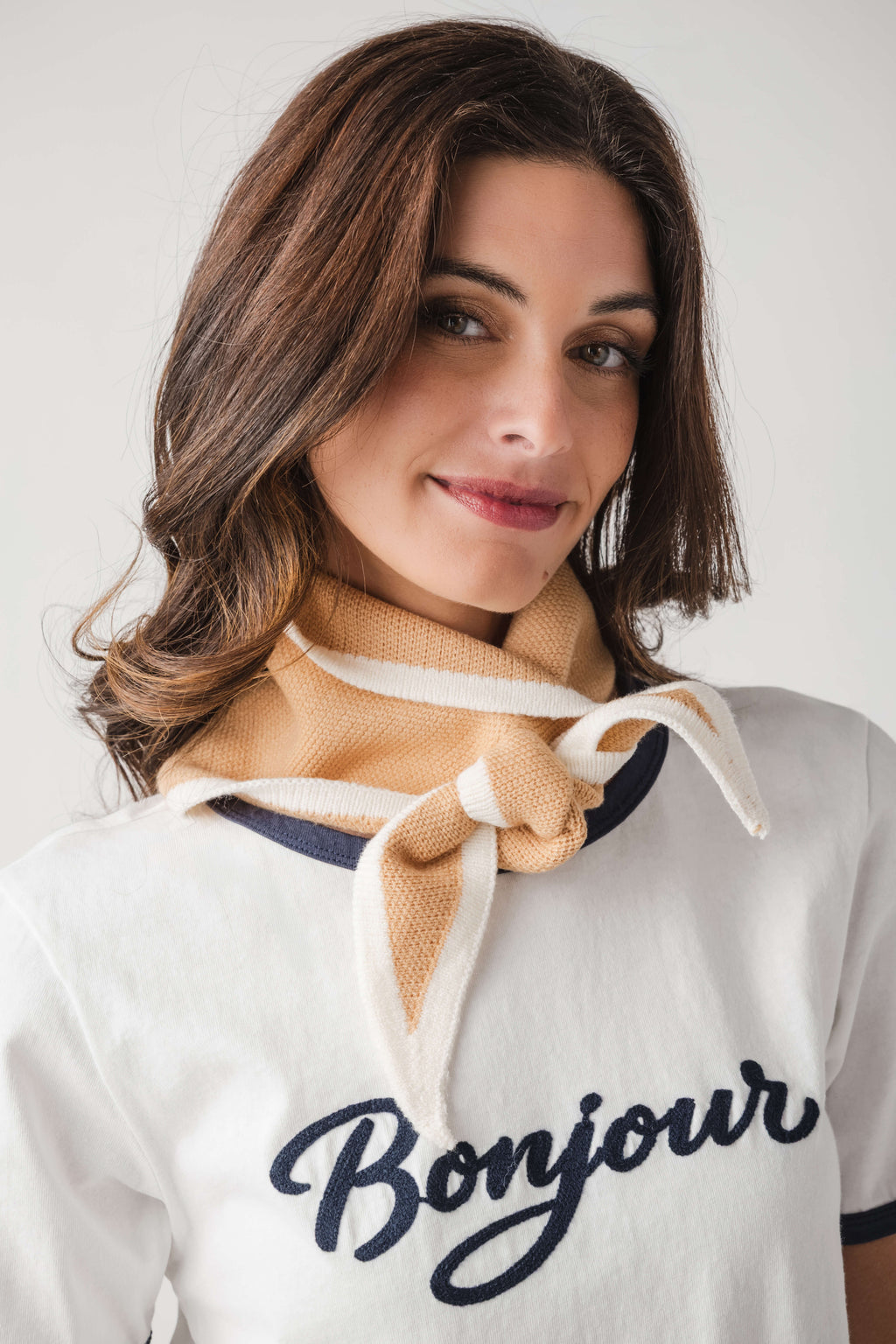 Khaki triangle knit scarf with cream-and-blue stripes, knotted at the neck