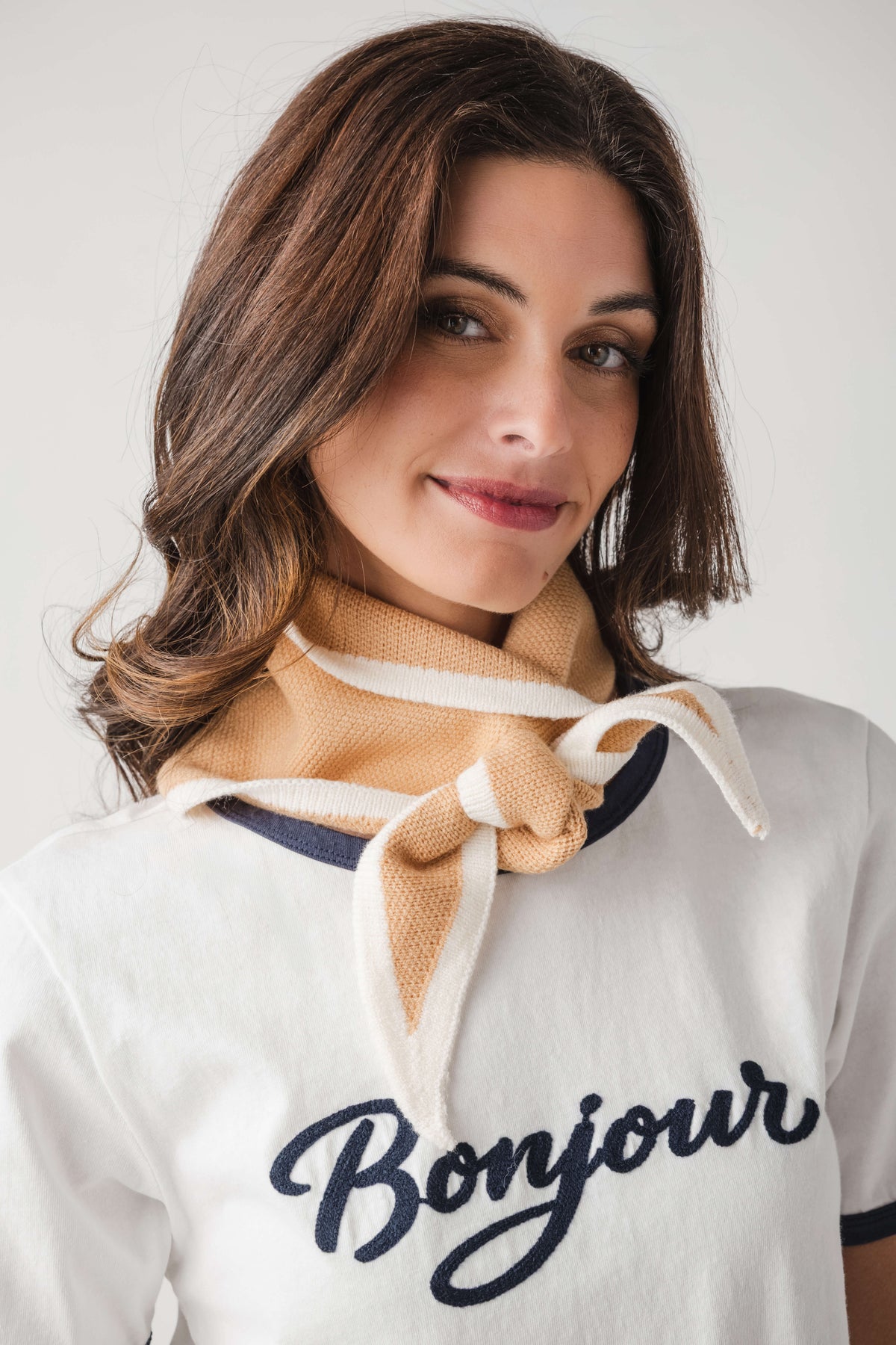 Khaki triangle knit scarf with cream-and-blue stripes, knotted at the neck