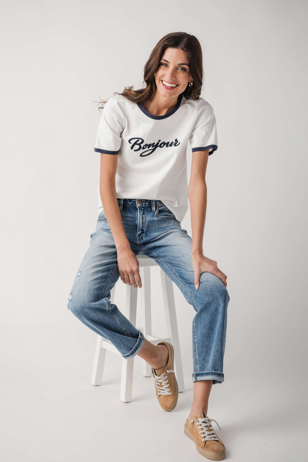 White Bonjour T-shirt with navy trim, styled with light-wash blue jeans and sneakers