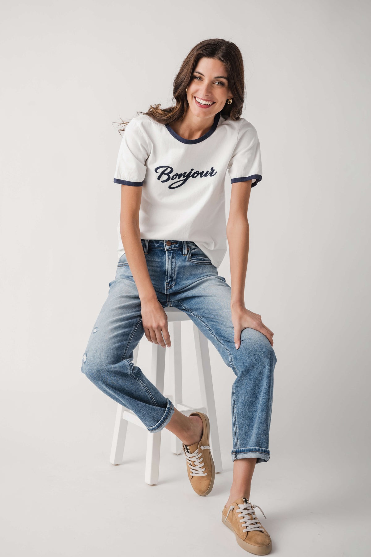 White Bonjour T-shirt with navy trim, styled with light-wash blue jeans and sneakers