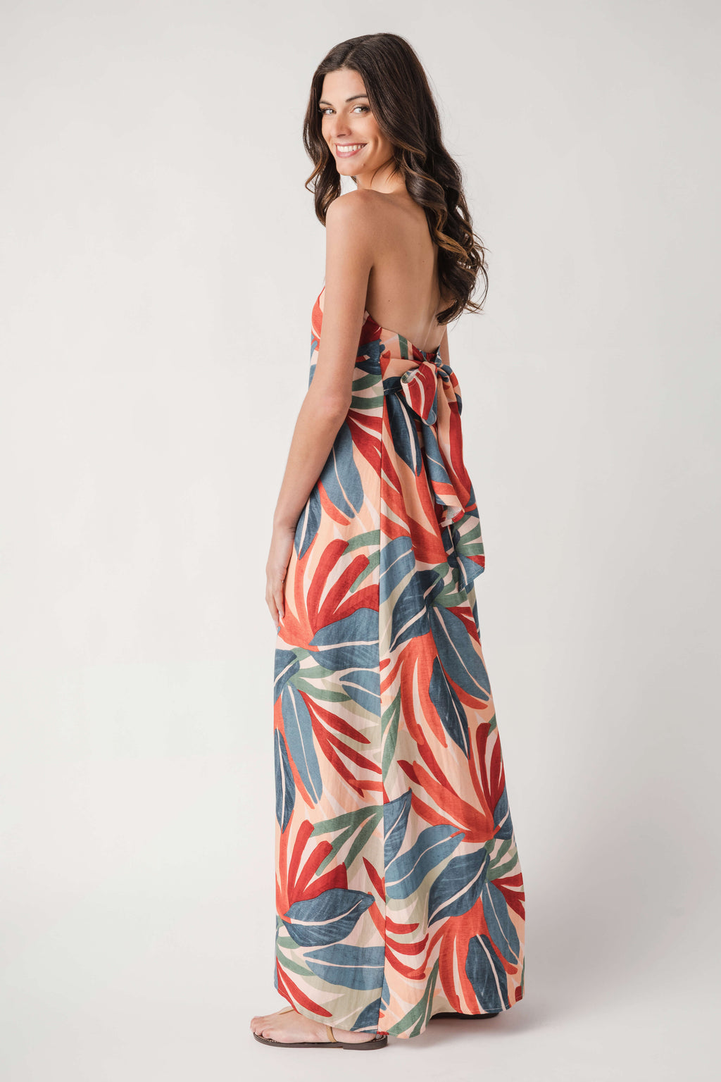 Strapless palm print maxi dress in orange, blue, and green, studio side view