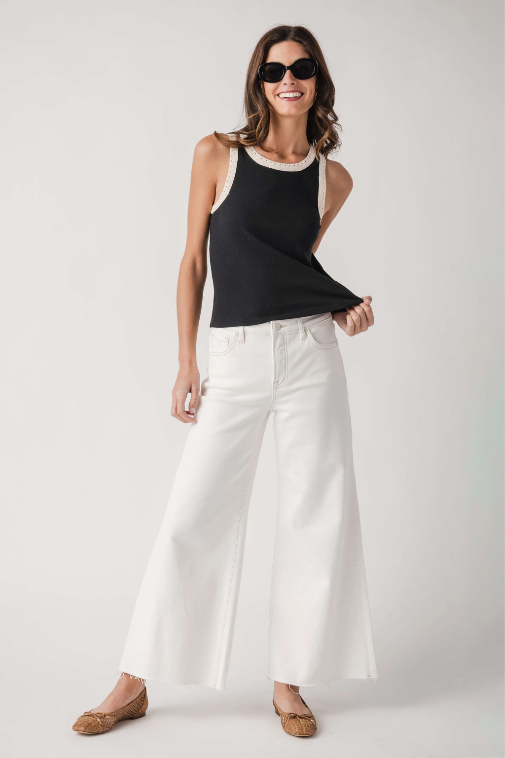 Black ribbed sleeveless tank with white contrast trim around neckline and armholes.