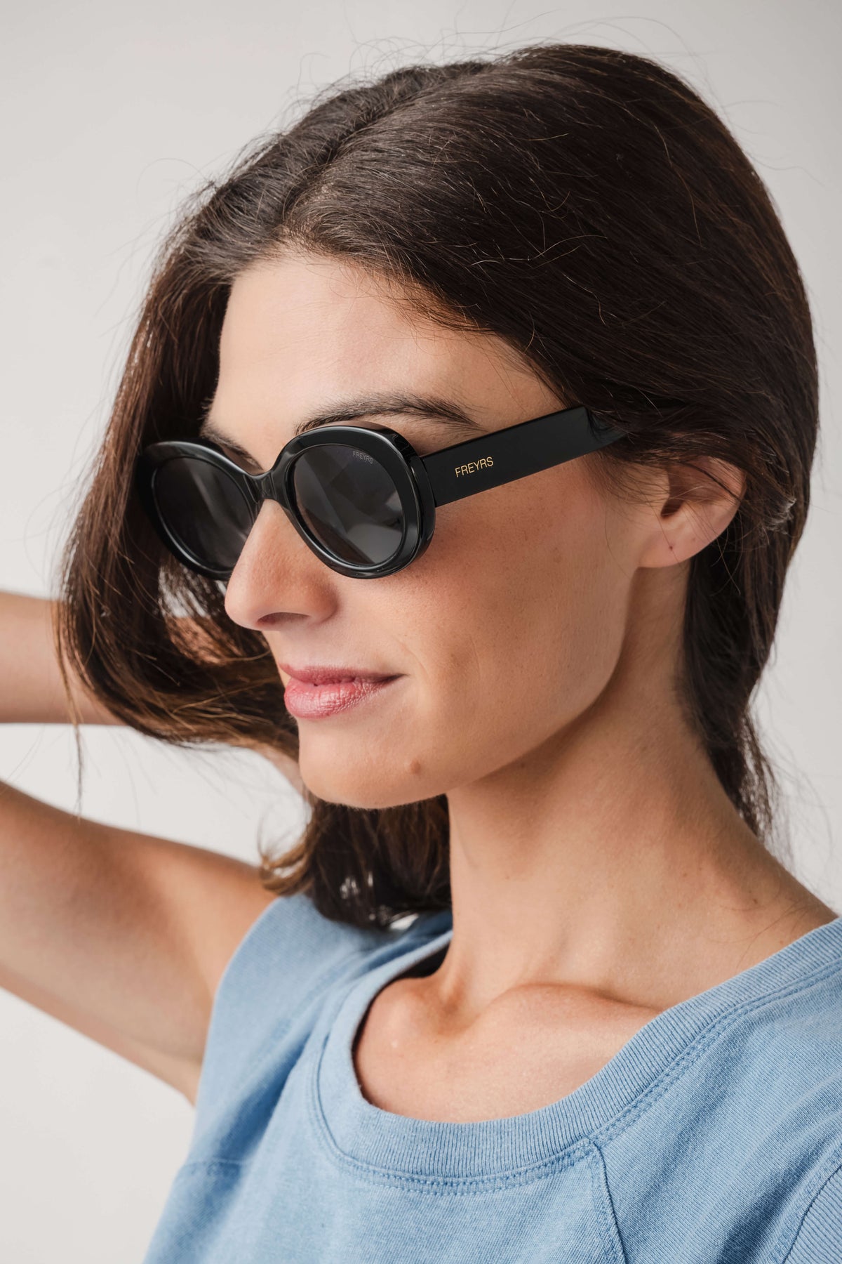 Freyrs Aria black round sunglasses with dark lenses, worn by model side profile