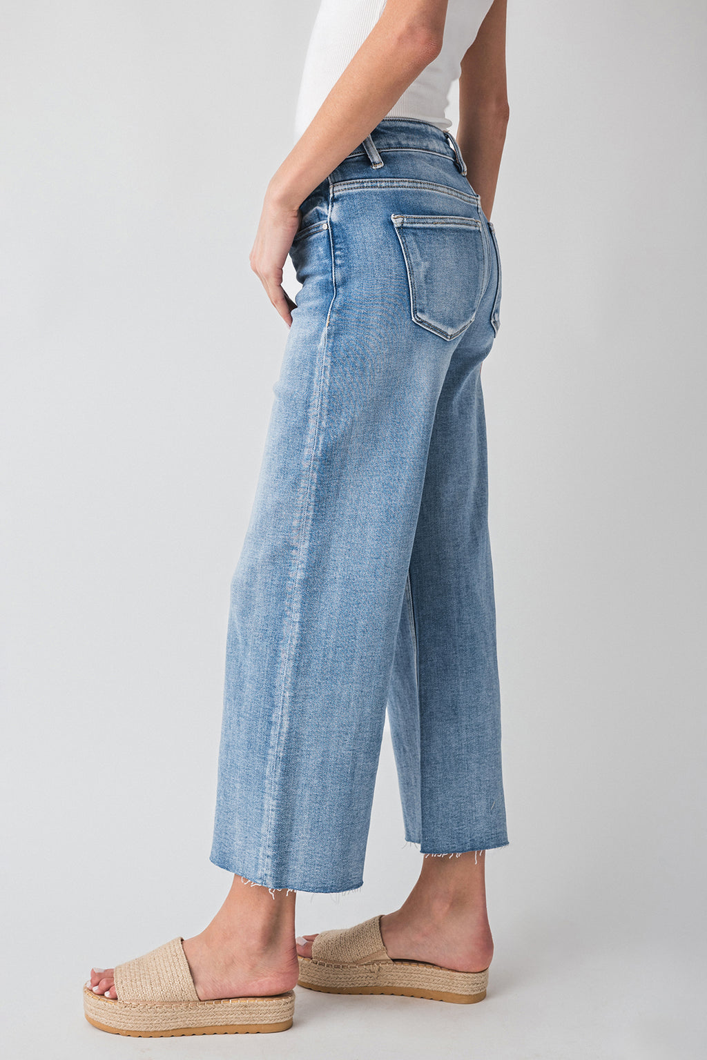 High-rise wide-leg light wash denim jeans with raw hem and back pocket detail