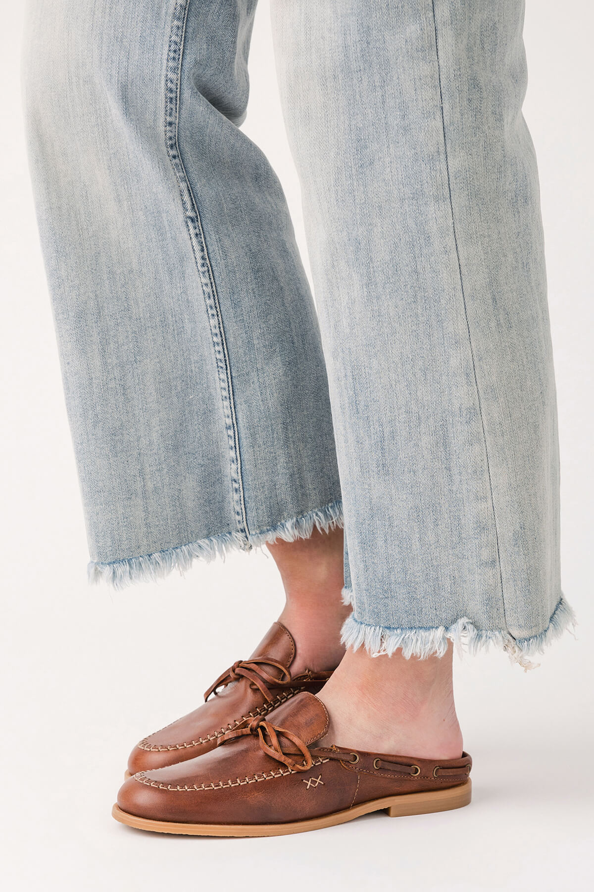 Brown slip-on mule loafers with stitch trim and braided strap across vamp