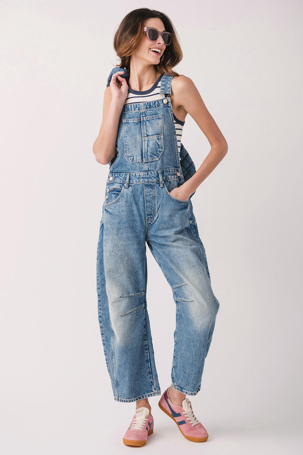 Orange low-top sneakers with white stripes and gum sole, styled with denim overalls.