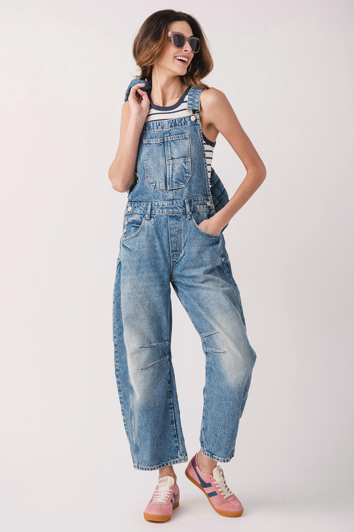 Orange low-top sneakers with white stripes and gum sole, styled with denim overalls.