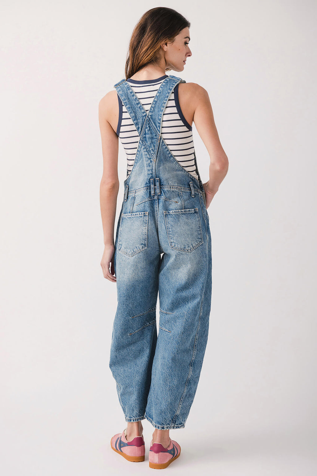 Light blue denim overalls from back view with crossback straps and wide legs.