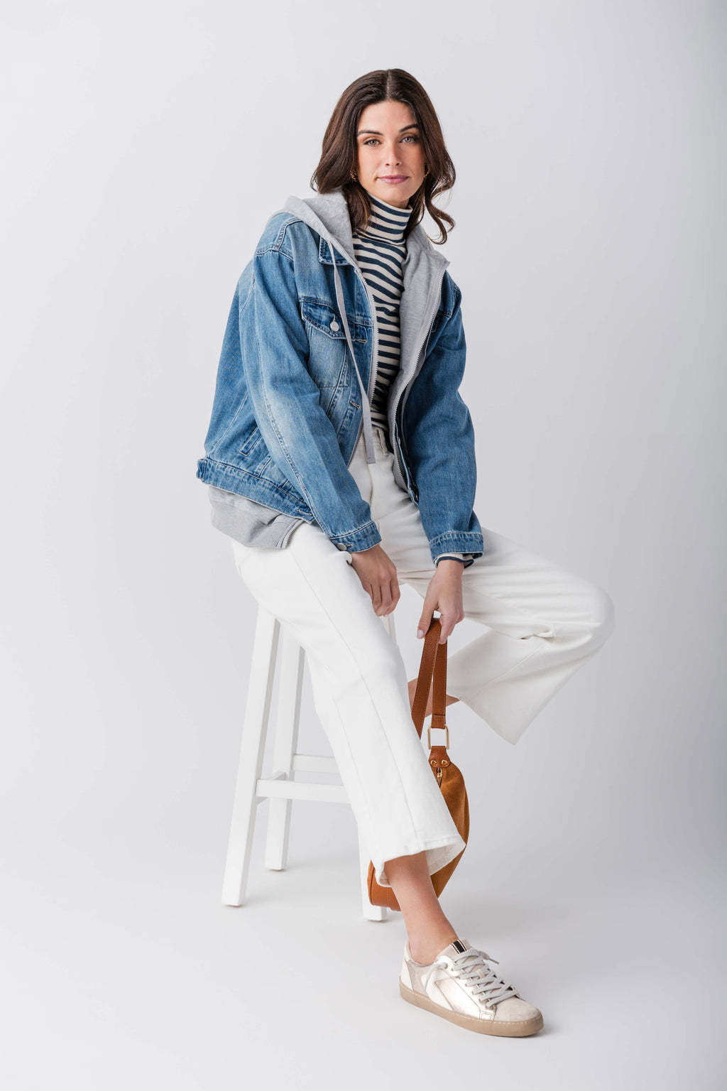 Blue denim sweatshirt jacket with gray hood and ribbed trim, seated pose view
