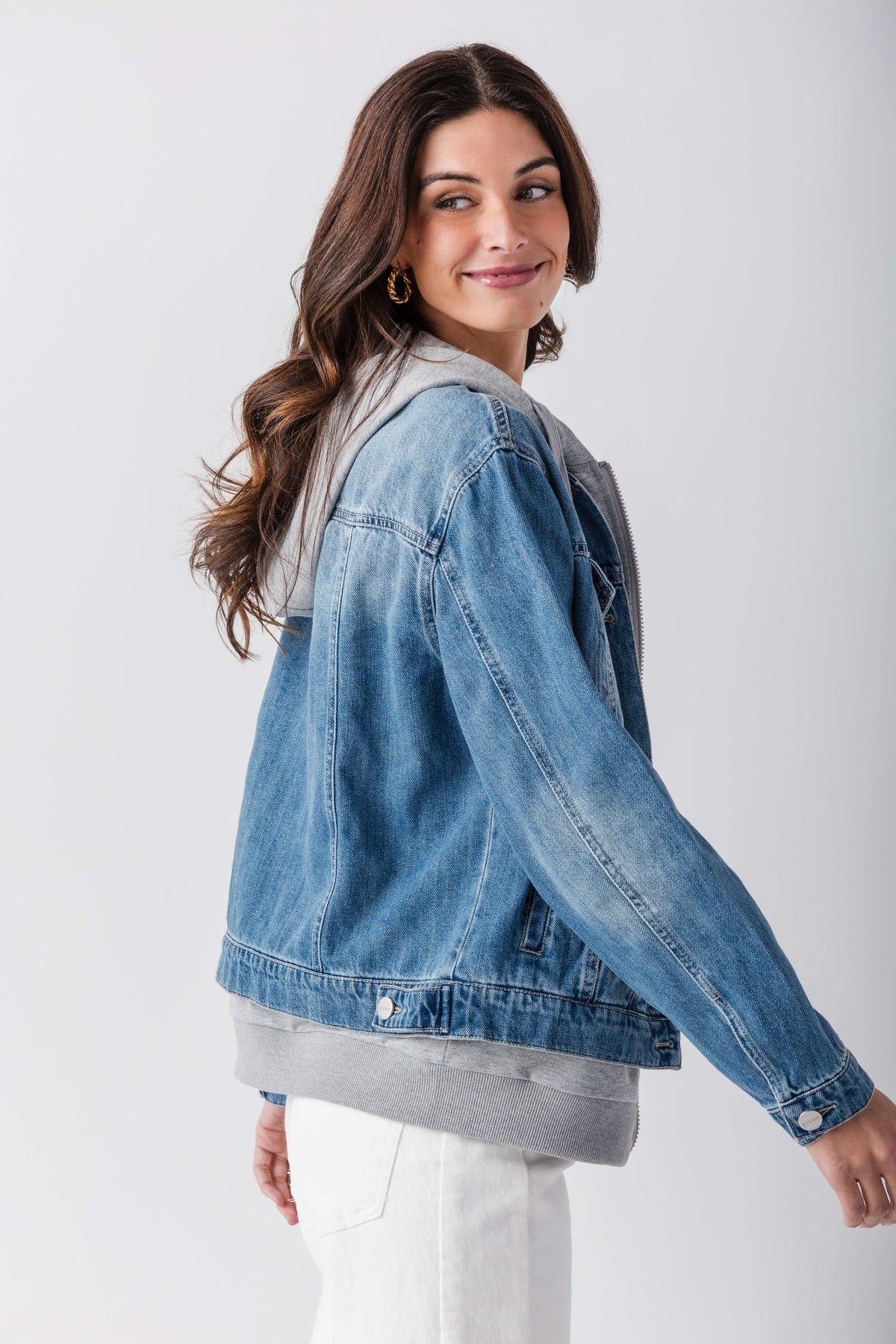 Blue denim sweatshirt jacket with gray hood and ribbed hem, angled side view