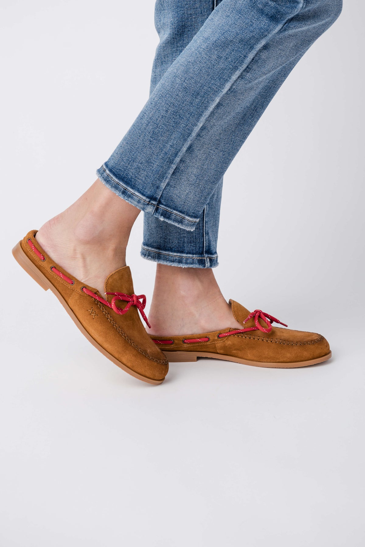 Brown suede slip-on mule flats with red lace bow and low-profile sole