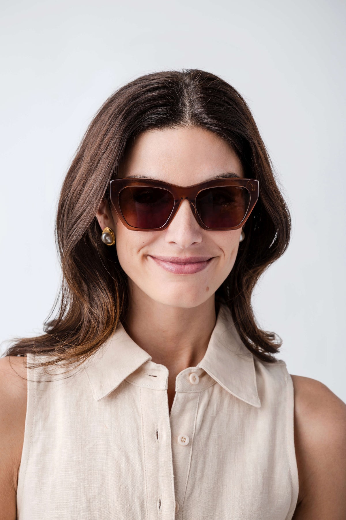 Woman wearing brown cat-eye sunglasses with amber tinted lenses