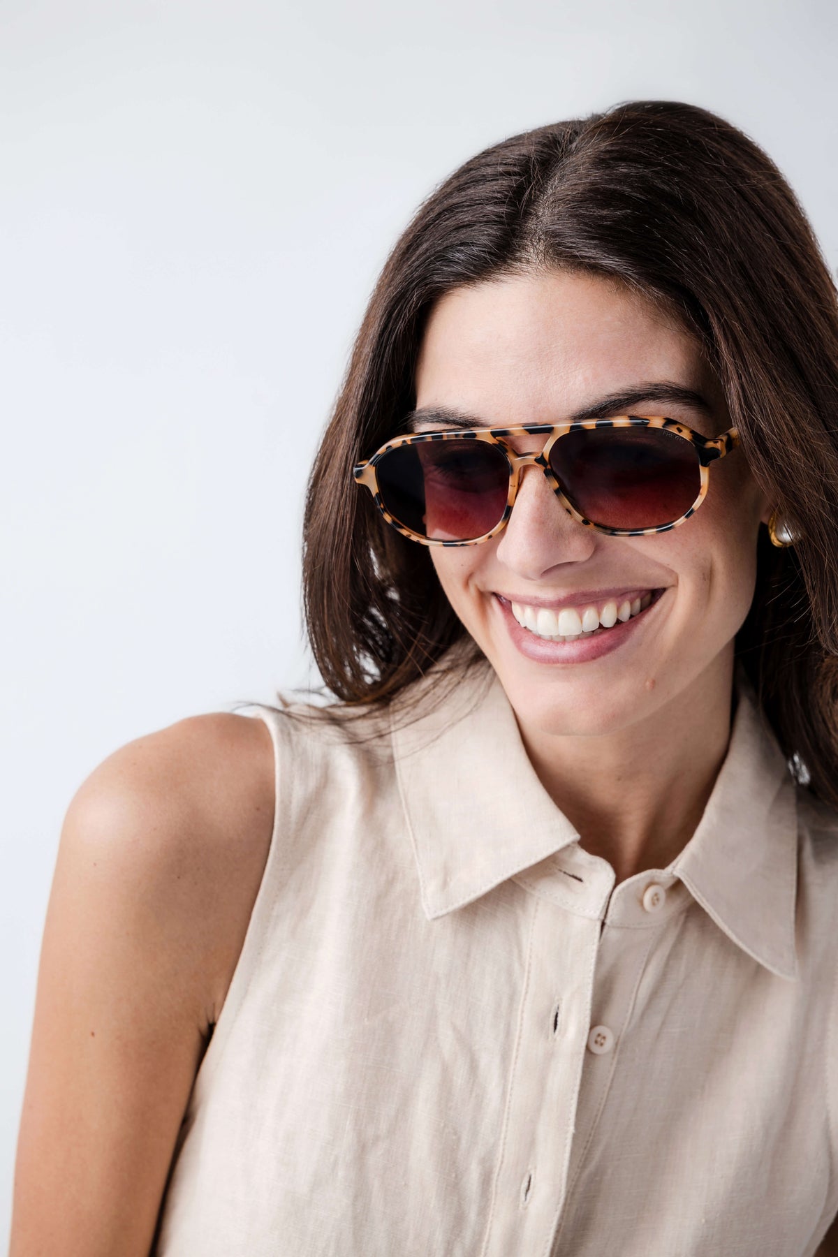 Milky tortoise aviator sunglasses on a smiling woman, dark tinted lenses