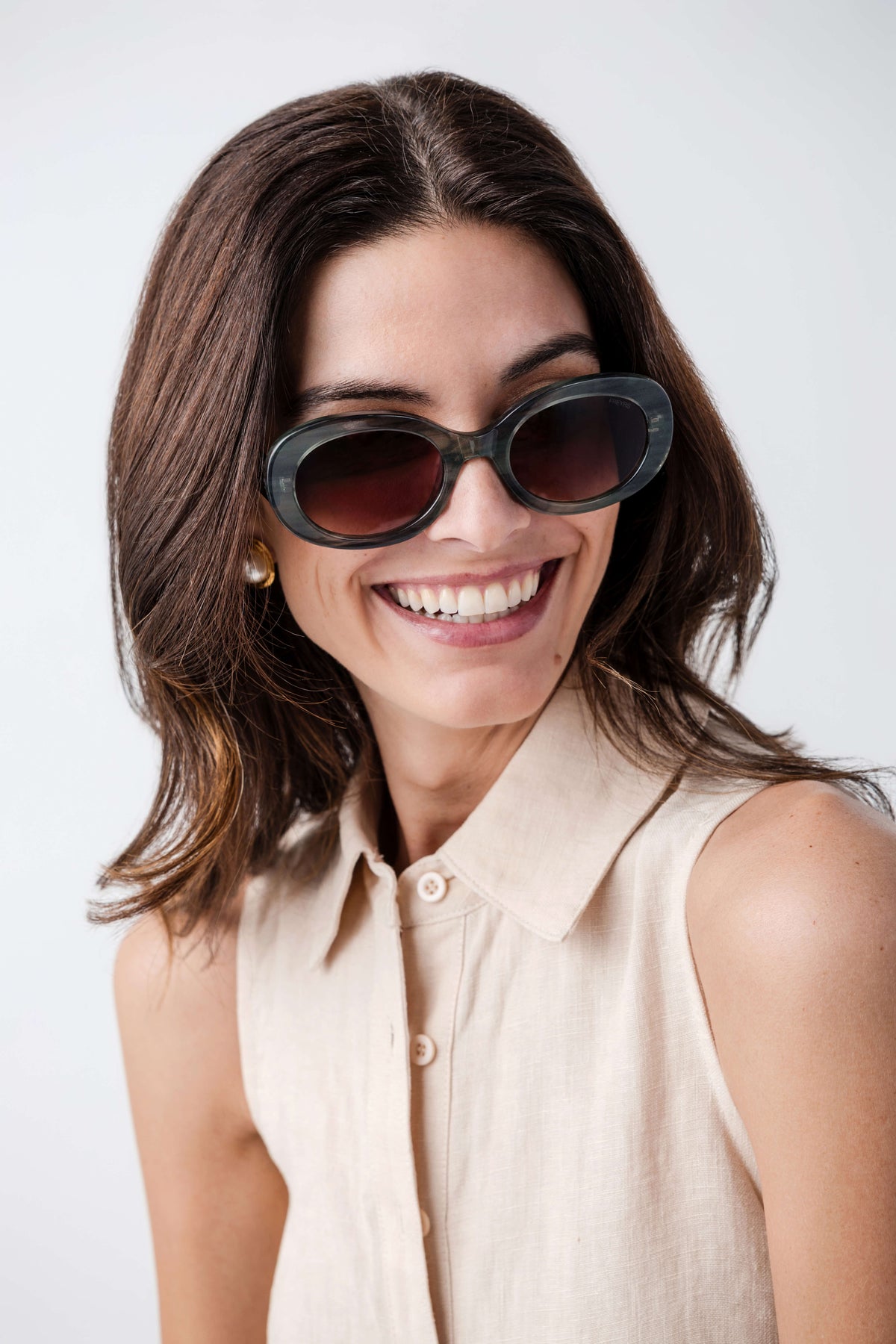 Freyrs Aria black oval sunglasses with dark lenses, worn by smiling model front view