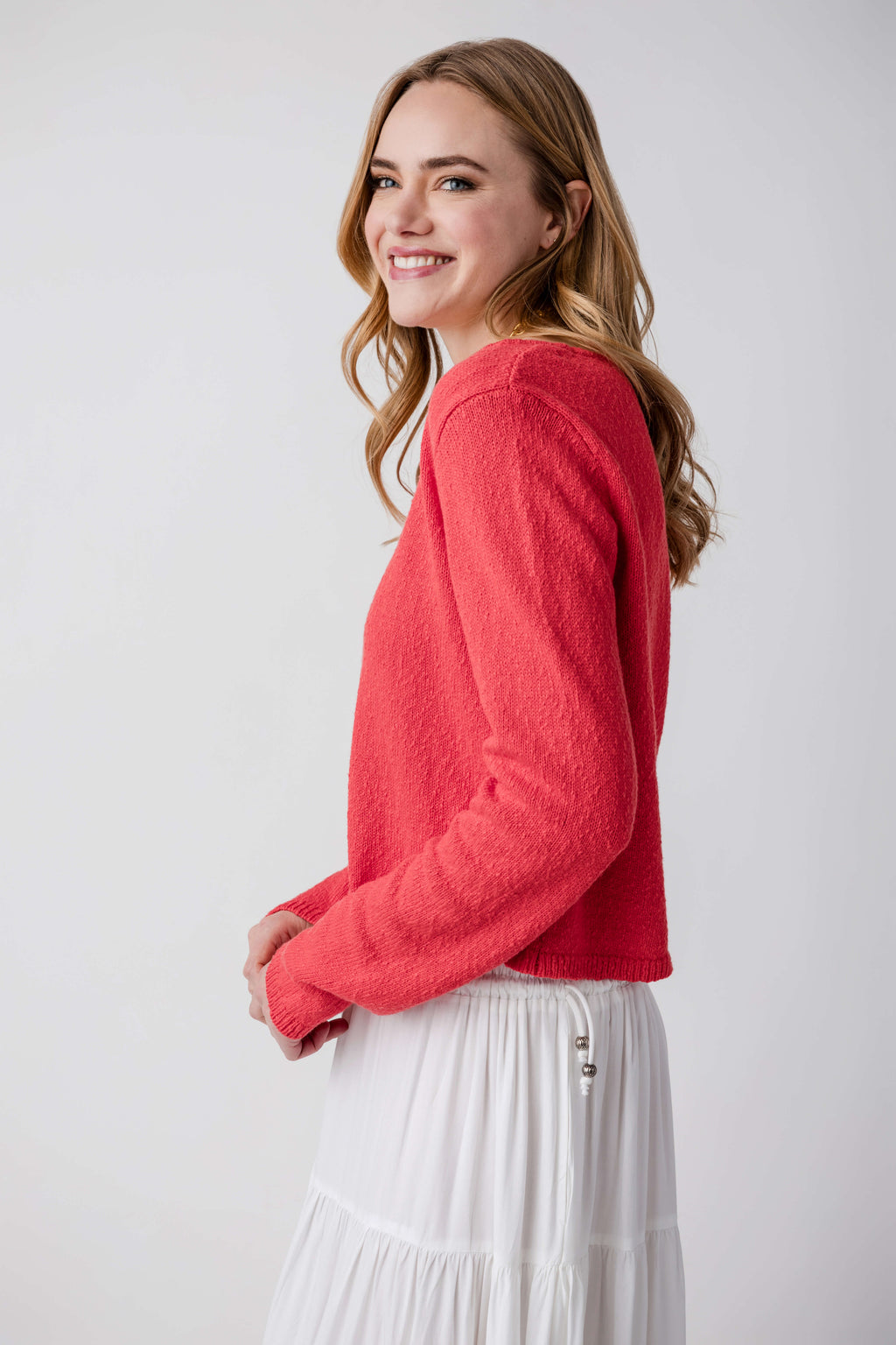 Tomato red V-neck cardigan with button front in profile view, long sleeves