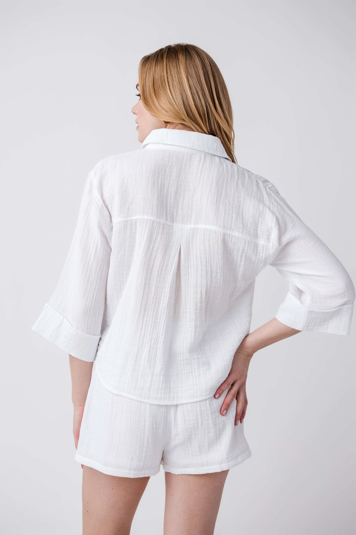 White button-front shirt from the back with chest pockets and rolled three-quarter sleeves