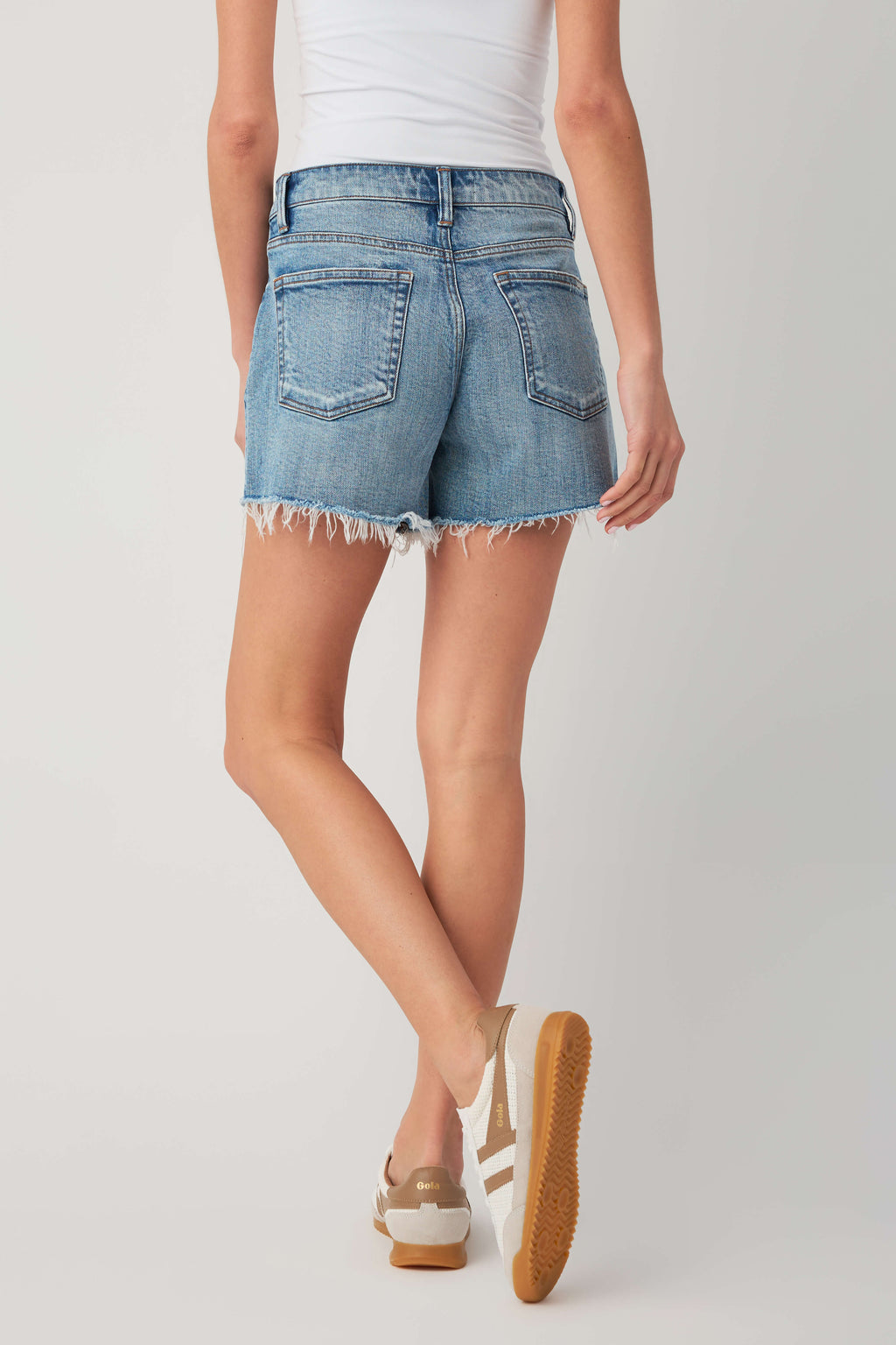 High-rise medium-wash denim shorts with raw frayed hem and front patch pocket