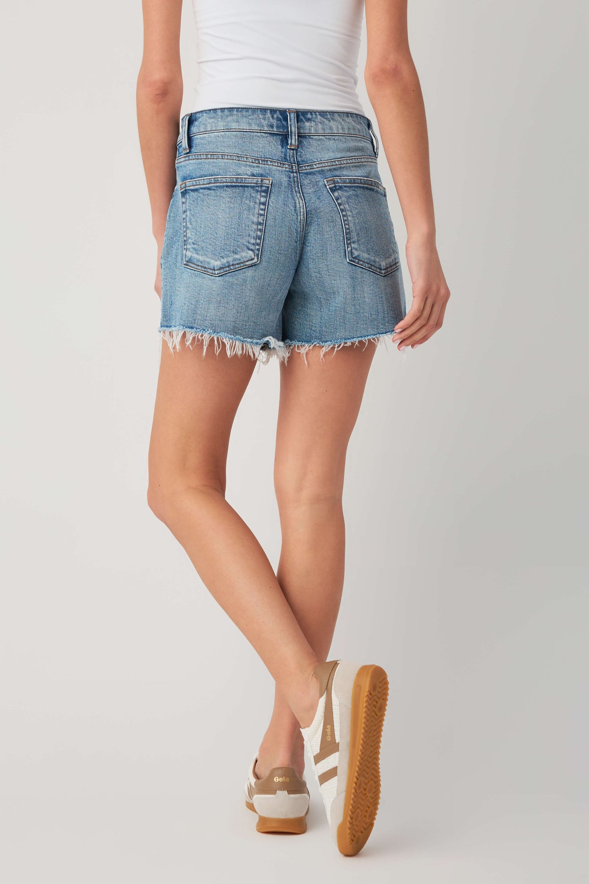 High-rise medium-wash denim shorts with raw frayed hem and front patch pocket
