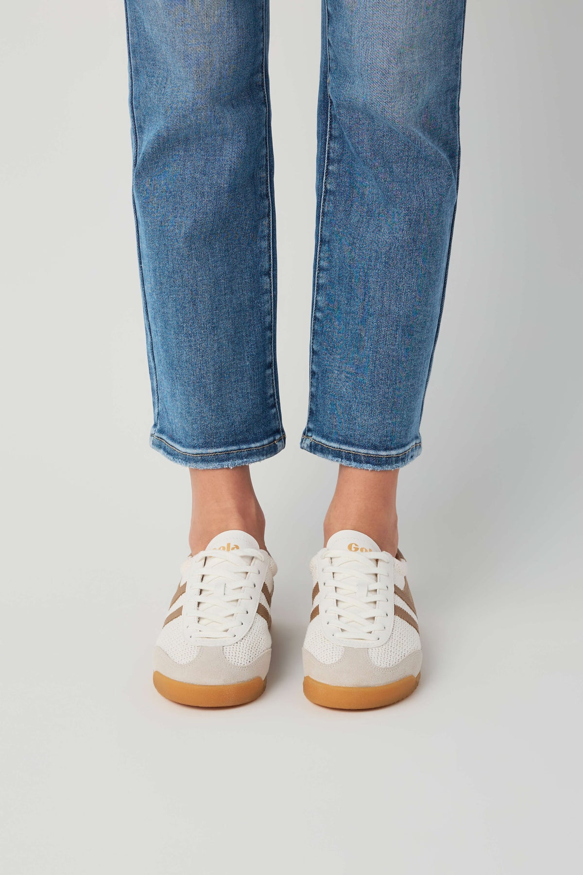 Off-white and tan low-top sneakers with lace-up front and gum rubber sole