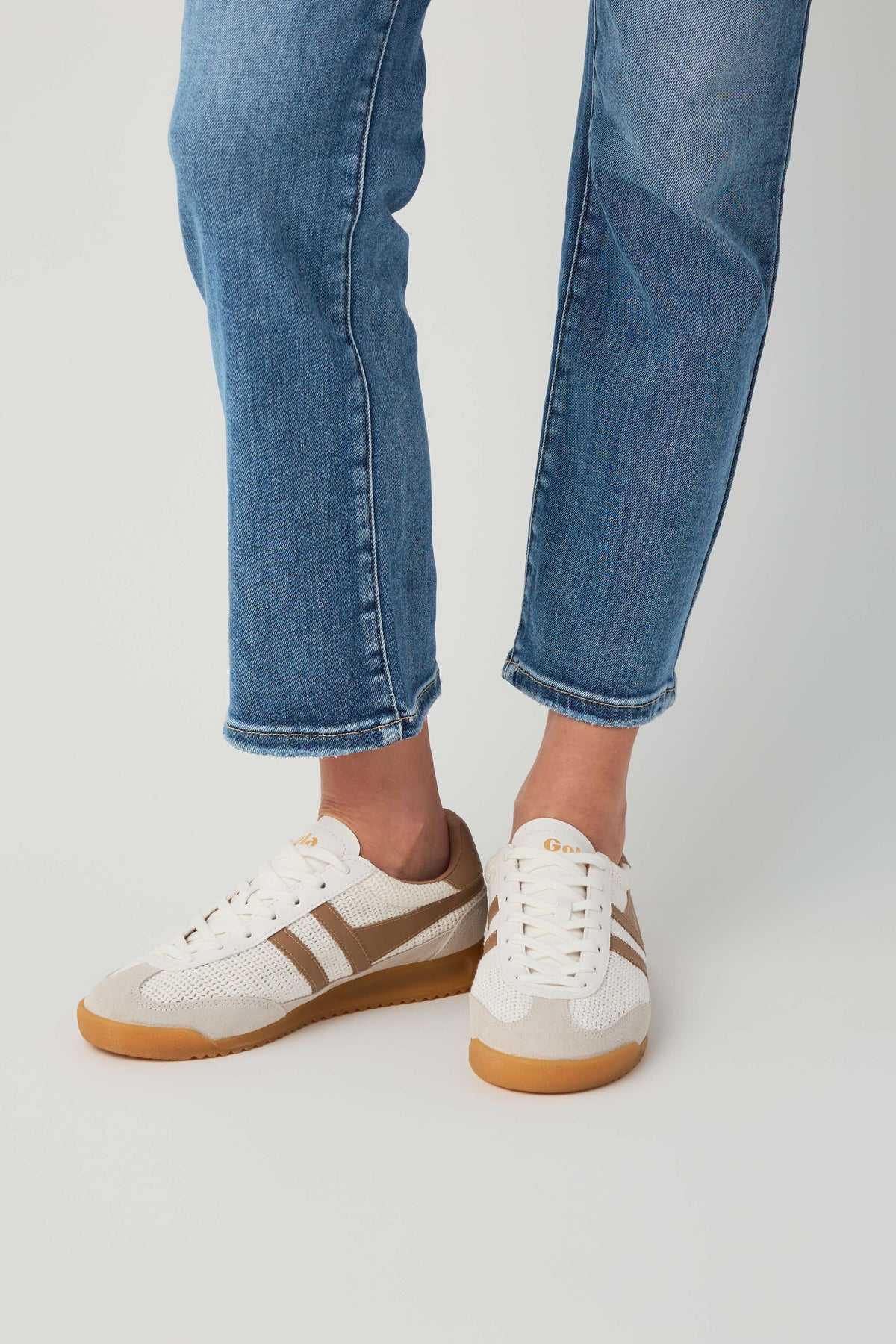 Off-white and tan low-top lace-up sneakers with side stripes and gum sole