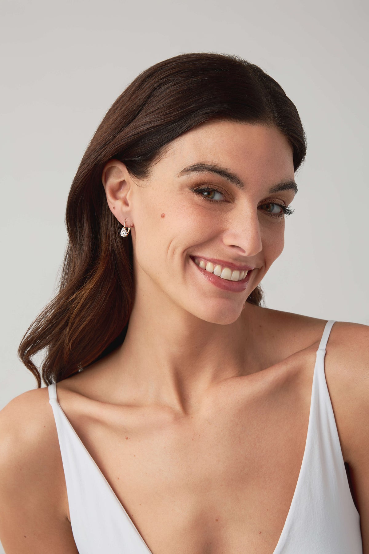 Woman wearing gold hoop earrings with clear oval crystal stone